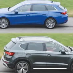Niebieskie auto kombi i ciemnoszare auto SUV jadą obok siebie po drodze.