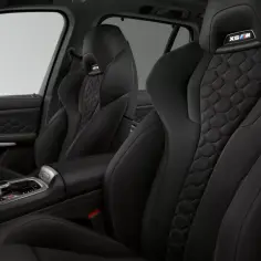 Wnętrze BMW X5 M z czarną, sportową tapicerką i wykończeniem w kształcie plastra miodu.