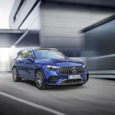 Niebieski suv Mercedes pędzi ulicą, otoczony nowoczesną architekturą.