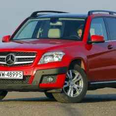 Czerwony Mercedes GLK na drodze. Kierowca za kierownicą. Wiele osób szuka mercedes glk opinie przed zakupem.