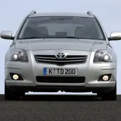 Srebrny kombi Toyota Avensis T25 z włączonymi światłami dziennymi i przeciwmgielnymi, gotowy do podróży.