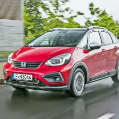 Czerwony Honda Jazz 4 na mokrej drodze, gotowy na miejskie przygody.
