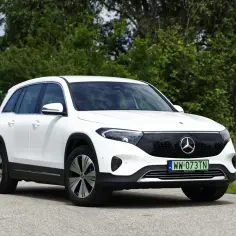 Biały Mercedes EQB stoi na drodze, otoczony zielenią.