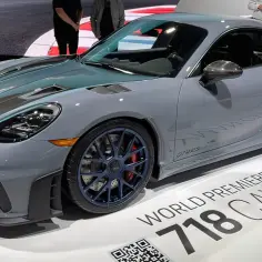 Szary Porsche GT4 RS z niebieskimi felgami i czerwonymi zaciskami hamulcowymi, prezentowany na wystawie.