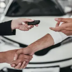 Kluczyki do nowego auta przekazywane w branży automotive. Uścisk dłoni symbolizuje udaną transakcję.