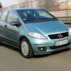 Turkusowy Mercedes A160 w ruchu drogowym, z widocznym kierowcą za kierownicą.
