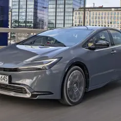 Szary Toyota Prius jedzie przez miasto, mijając nowoczesne budynki.