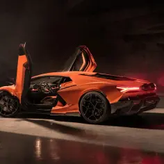 Pomarańczowy Lamborghini Revuelto z otwartymi drzwiami, gotowy do jazdy.