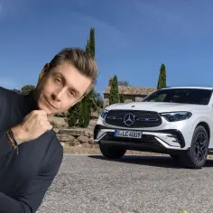 Mężczyzna zamyślony obok białego Mercedesa GLC AMG na tle słonecznej Toskanii.