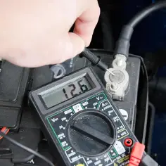 Sprawdzanie akumulatora multimetrem. Wynik 12.6V pokazuje, że jest naładowany.