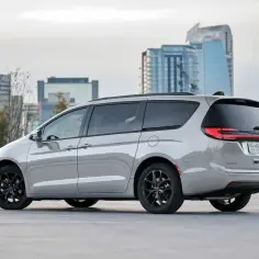 Srebrny Chrysler Pacifica z czarnymi felgami na tle miejskiej panoramy.