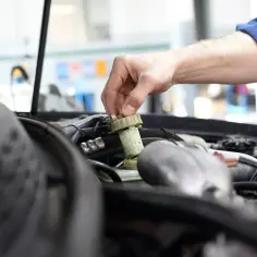 Ręka mechanika dokręca korek zbiorniczka płynu hamulcowego. Czas na badanie techniczne po terminie, by uniknąć problemów.