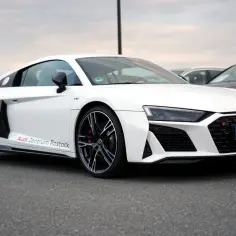 Białe Audi RS8 z napisem "Audi Zentrum Rostock" na progu, zaparkowane na asfalcie.