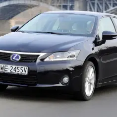 Czarny Lexus CT 200h jedzie po drodze, z mostem w tle.
