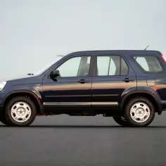 Ciemnoniebieski Honda CRV 2005 z kołem zapasowym z tyłu, zaparkowany na pustej drodze o zachodzie słońca.