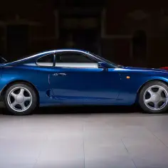 Niebieska Toyota Supra w towarzystwie czerwonych klasyków. Sprawdź aktualną toyota supra cena i znajdź swój wymarzony samochód.