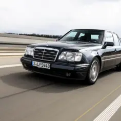 Czarny Mercedes 500E pędzi autostradą, jego sylwetka jest dynamiczna i elegancka.