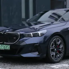 Eleganckie BMW i5 w ciemnym kolorze, z charakterystycznym podświetleniem atrapy chłodnicy i nowoczesnymi światłami.