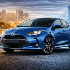 Niebieski Toyota Yaris Hybrid lśni na tle nocnego miasta.