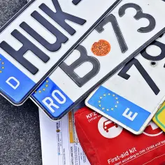 Niemieckie, rumuńskie i inne tablice rejestracyjne leżą obok apteczki. Kn rejestracja w różnych krajach.