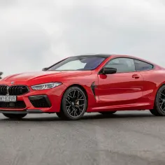 Czerwone BMW 840d coupe na torze wyścigowym, z czarnymi felgami i detalami.