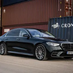 Czarny Mercedes S 500 lśni na tle kontenerów. Elegancka limuzyna prezentuje się okazale.