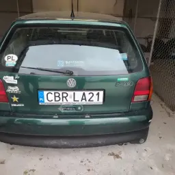 Zielony Volkswagen Polo z naklejkami, w tym "Jedź bezpiecznie" i "PL". Tablica rejestracyjna CBR LA21. Brak rejestracji widocznej na zdjęciu.