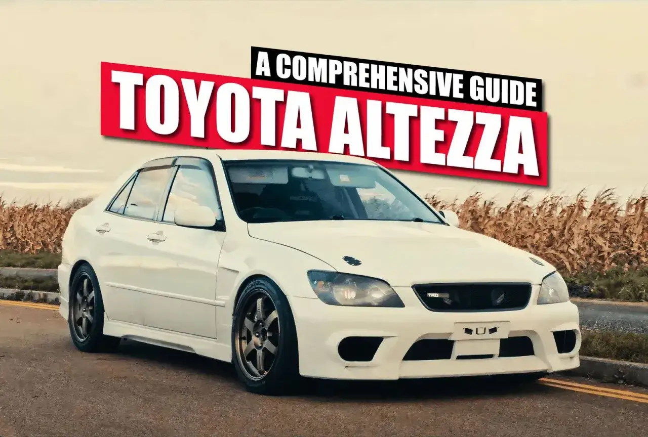 Biała Toyota Altezza z tuningowym zderzakiem i felgami stoi na tle pola.