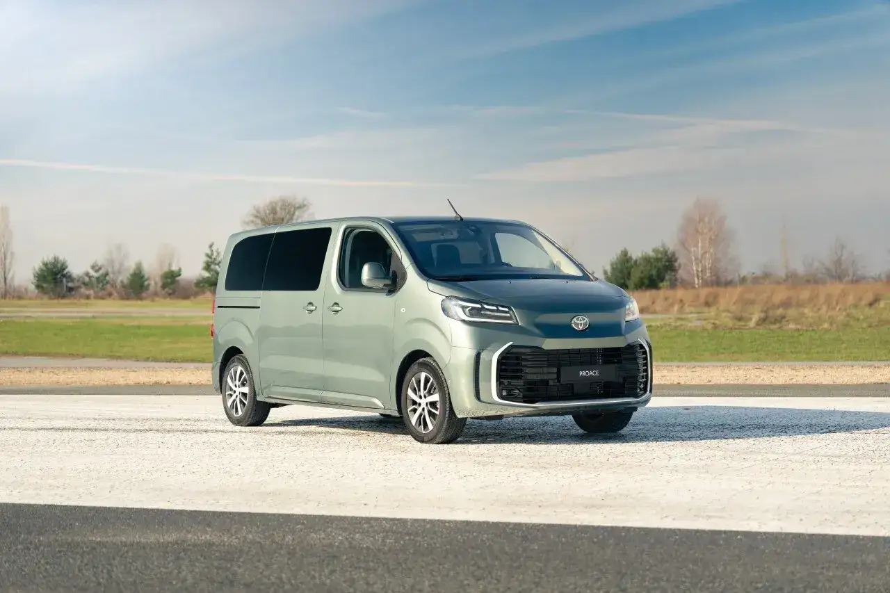 Nowy, zielony Toyota Proace Verso na tle nieba i pól.