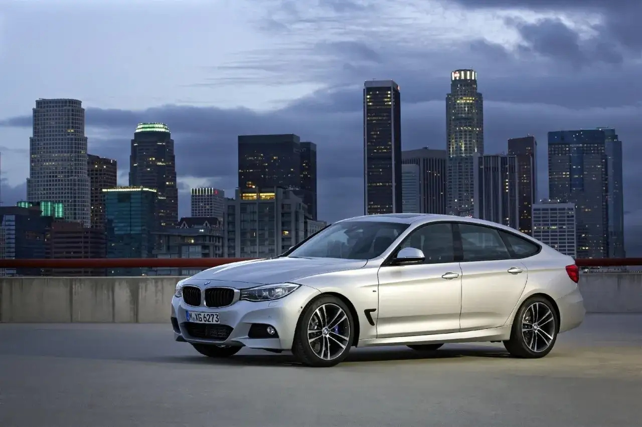 Srebrne BMW 3GT na tle nocnej panoramy miasta.