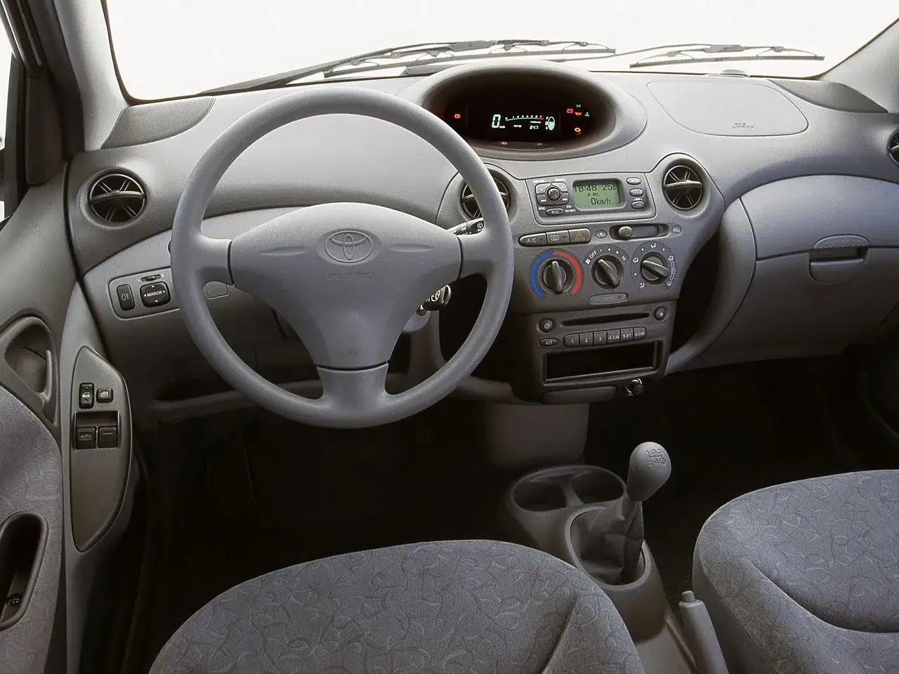 Wnętrze Toyoty Yaris 1. Kierownica, deska rozdzielcza z radiem i klimatyzacją, dźwignia zmiany biegów.