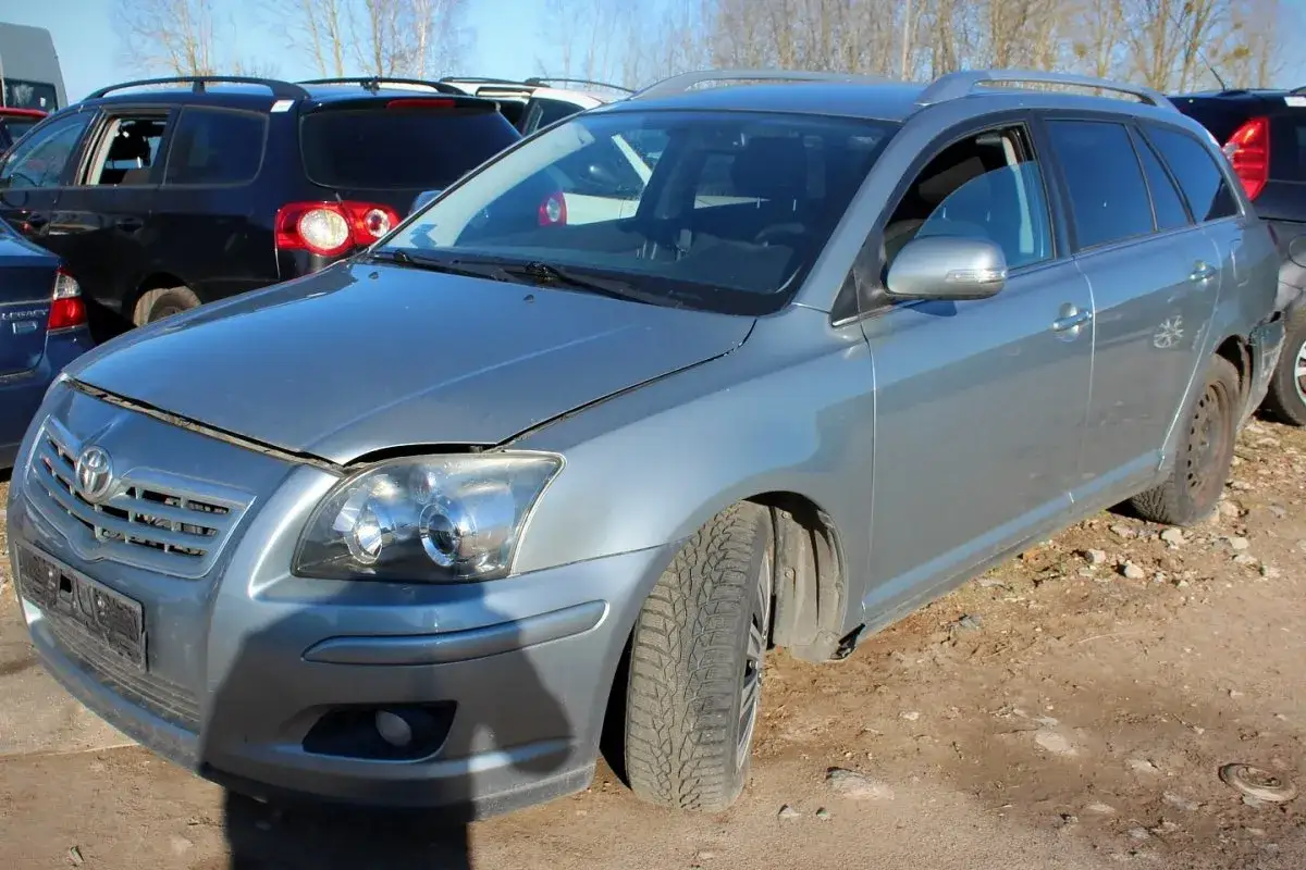 Szary kombi Toyota Avensis T25 stoi na placu złomowiska.