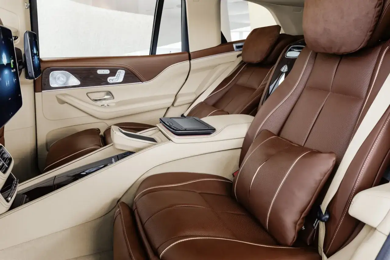 Luksusowe wnętrze Maybach GLS 600 z brązowymi skórzanymi fotelami, ekranami i eleganckimi detalami.