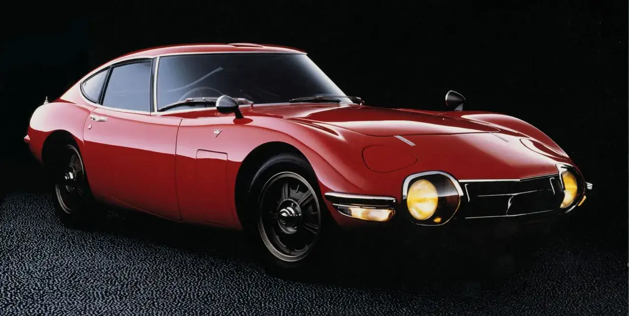 Klasyczny, czerwony Toyota 2000GT z lat 60. z błyszczącym lakierem i okrągłymi reflektorami.