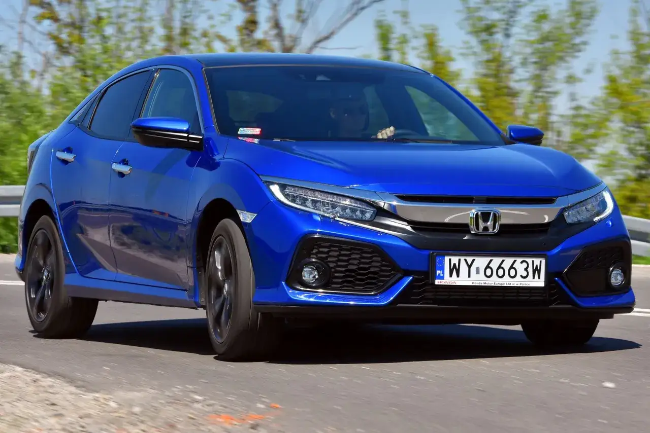 Błękitny Honda Civic 2017 pędzi po drodze, kierowca w okularach przeciwsłonecznych.