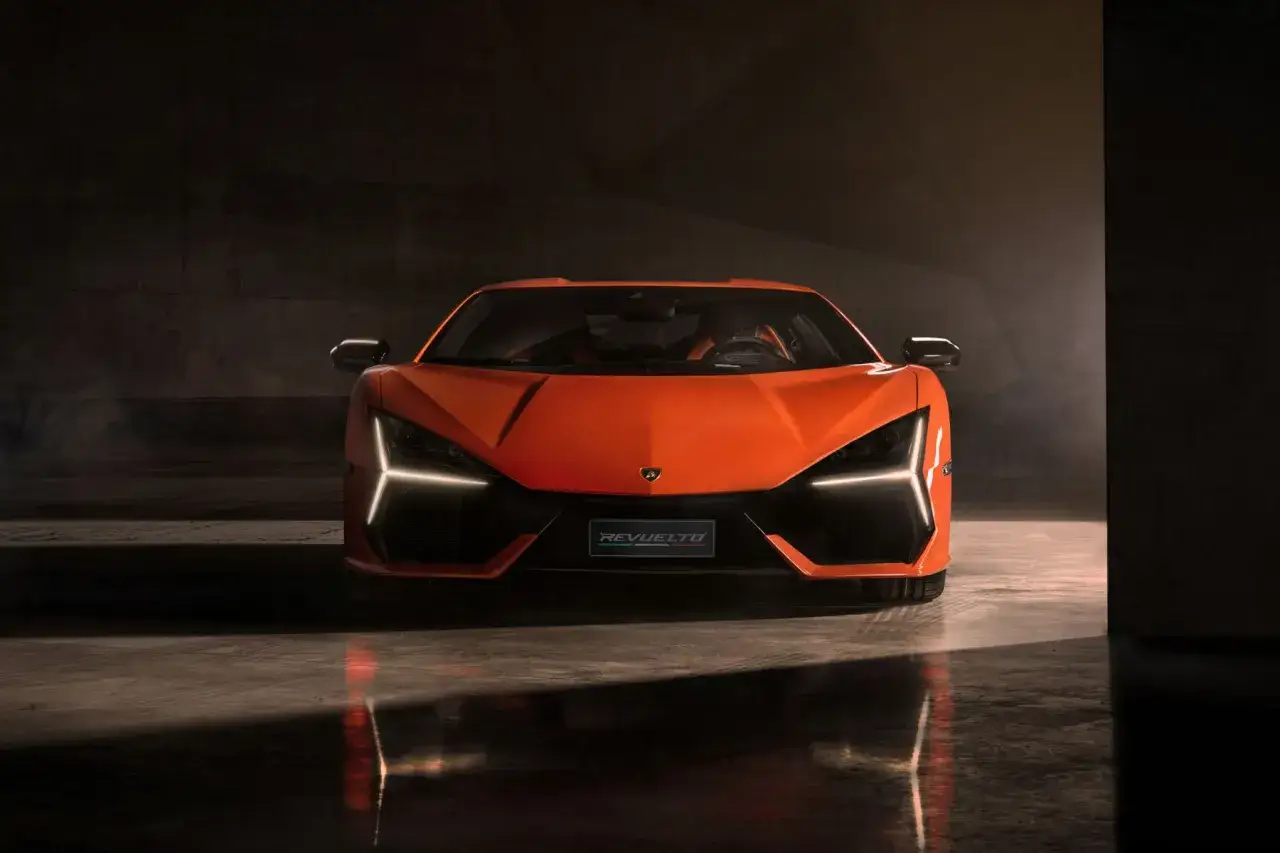 Pomarańczowy Lamborghini Revuelto z ostrymi światłami LED, prezentujący swoją agresywną sylwetkę w mrocznym, industrialnym otoczeniu.