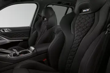 Wnętrze BMW X5 M z czarną, sportową tapicerką i wykończeniem w kształcie plastra miodu.