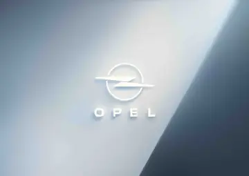 Białe, przestrzenne litery OPEL i okrąg z błyskawicą, symbolizujące markę Opel, na tle gradientu od jasnego błękitu do granatu.
