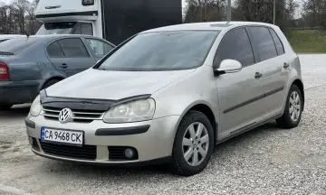 Złoty Volkswagen Golf z ukraińską tablicą rejestracyjną UA CA 9468 CK stoi na parkingu.