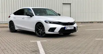 Biały Honda Civic 2025 z czarnymi felgami stoi na parkingu.