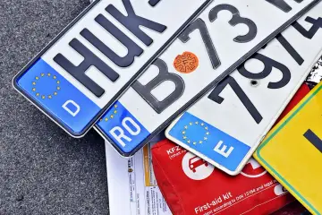 Niemieckie, rumuńskie i inne tablice rejestracyjne leżą obok apteczki. Kn rejestracja w różnych krajach.
