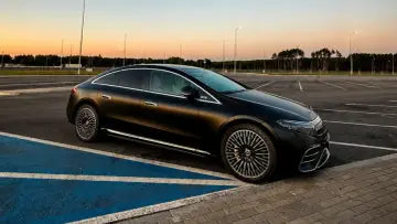Elegancki, czarny Mercedes EQS na pustym parkingu o zachodzie słońca.