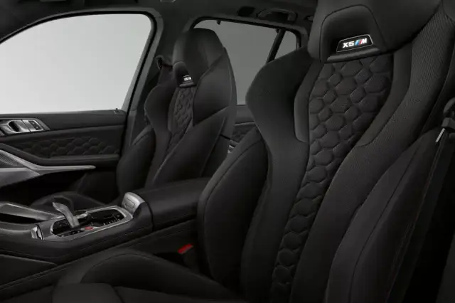Wnętrze BMW X5 M z czarną, sportową tapicerką i wykończeniem w kształcie plastra miodu.