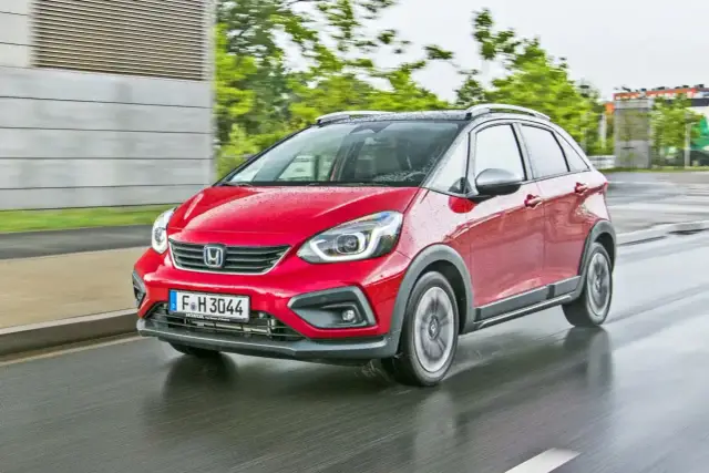 Czerwony Honda Jazz 4 na mokrej drodze, gotowy na miejskie przygody.